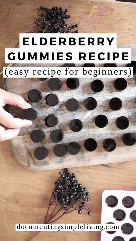 An overhead shot of elderberry gummies on a wooden cutting board next to fresh elderberries.