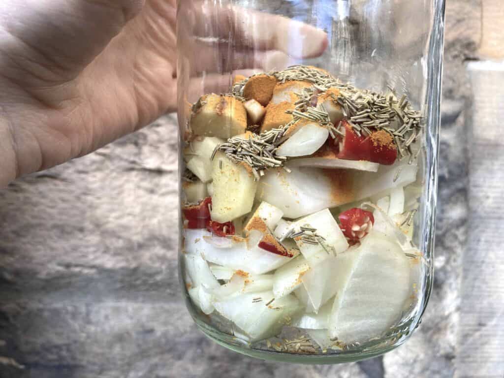 Onions, garlic, ginger, hot peppers, rosemary, and tumeric in a glass jar.