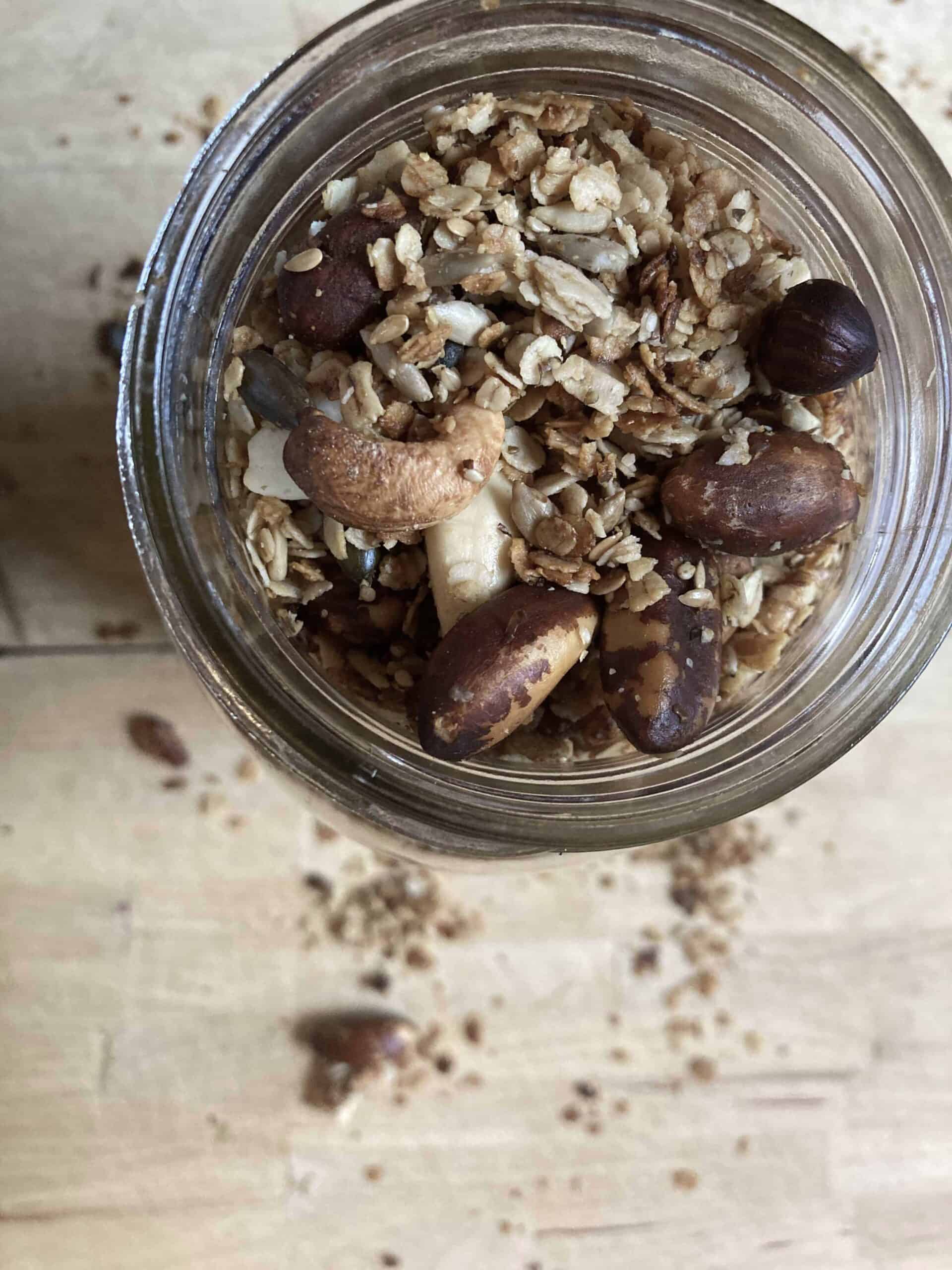 Homemade high protein granola in a glass jar on a wooden cutting board