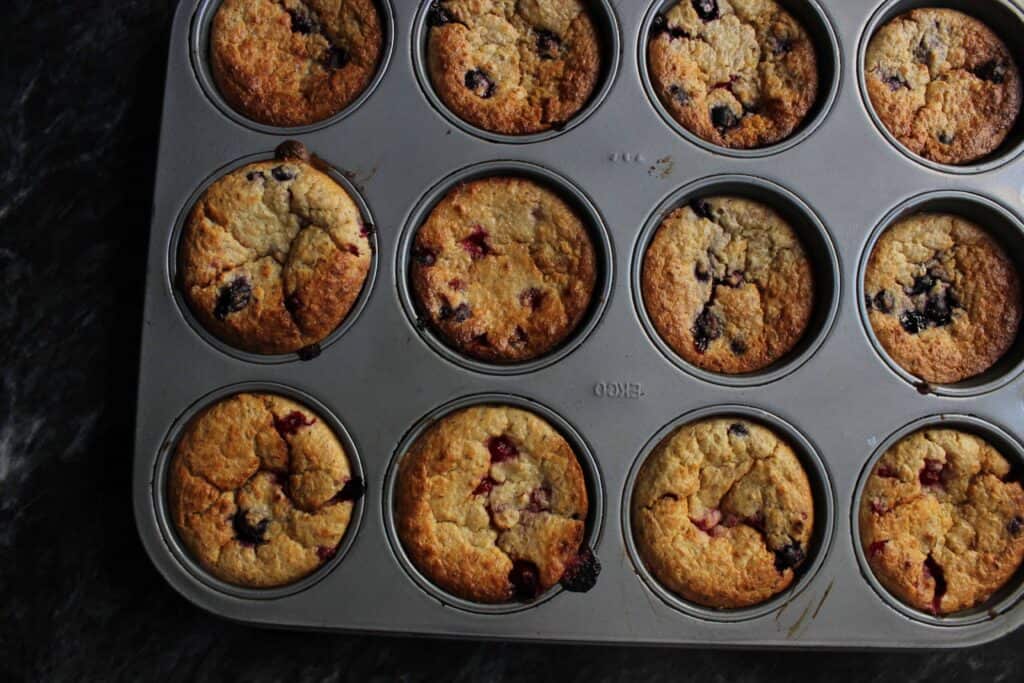 A muffin tin with baked blueberry banana oatmeal muffins
