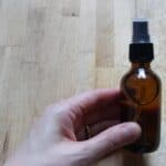 A person holding a small glass amber spray bottle.