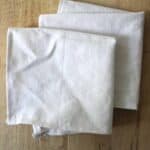 Two DIY linen napkins folded on a light wooden background.