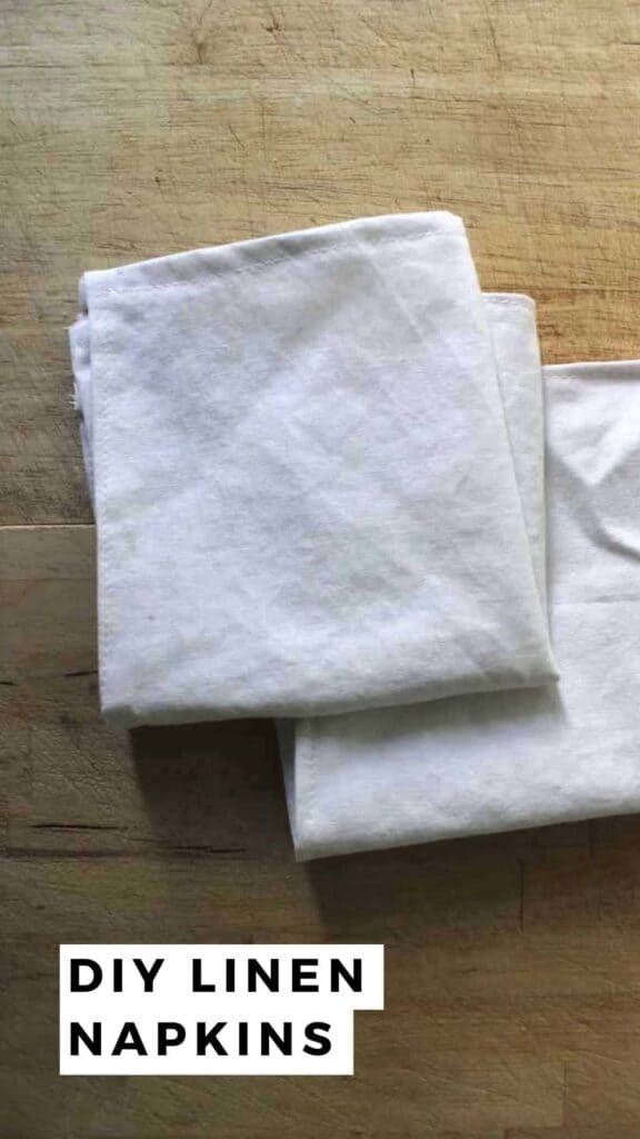 Two DIY linen napkins folded on a light wooden background.