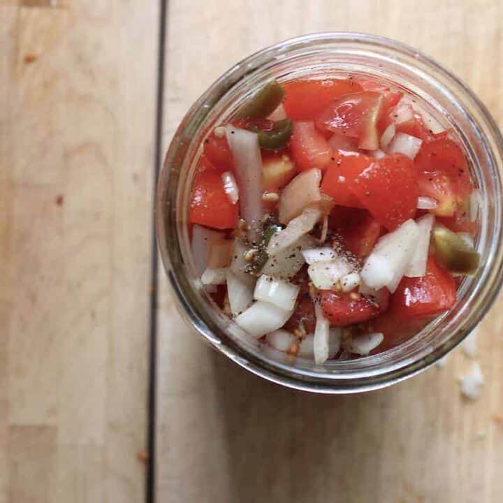 An overhead shot of a glass mason jar with tomato relish.