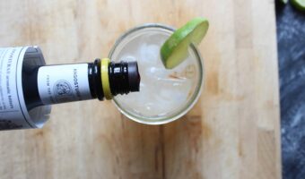 An overhead shot of lemon lime and bitters drink in a glass jar with the bitters being poured into the top of the glass jar.