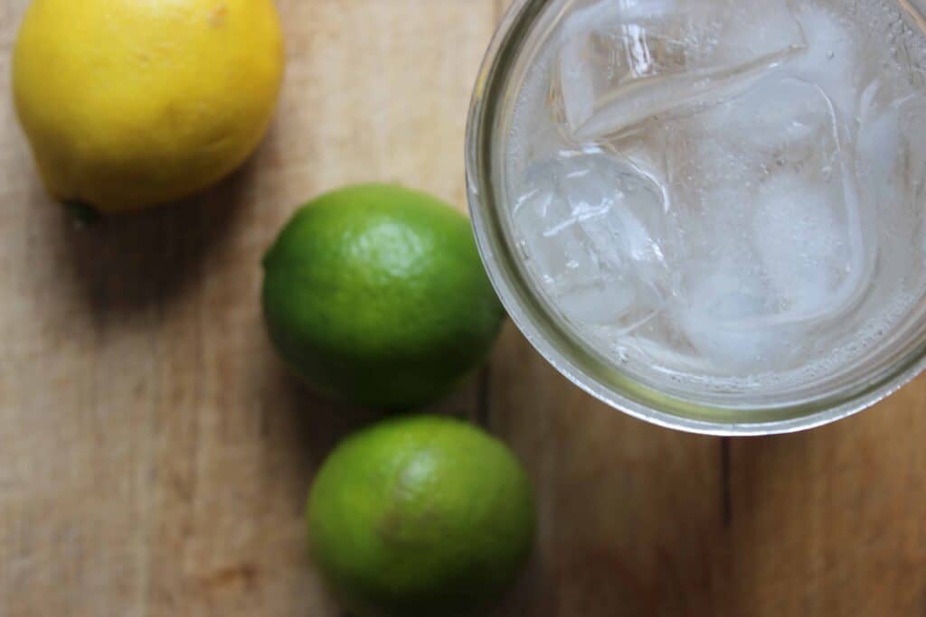 An overhead shot of lemons and limes next to a lemon lime and bitters drink.