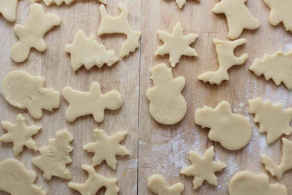 Sugar cookies that are in Christmas shapes on a light background before being baked.