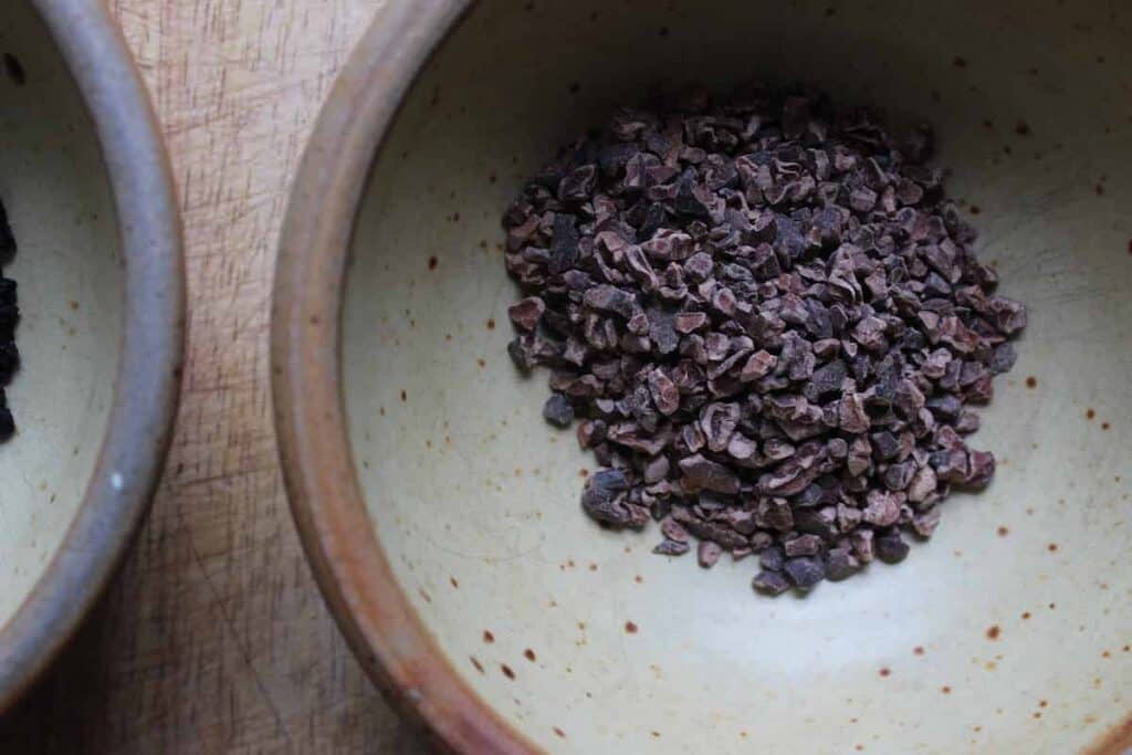 An overhead shot of cacao nibs in a pottery bowl.