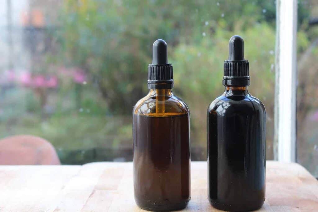 Two amber glass bottles with homemade echinacea tincture on a windowsill.
