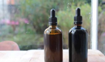 Two amber glass bottles with homemade echinacea tincture on a windowsill.
