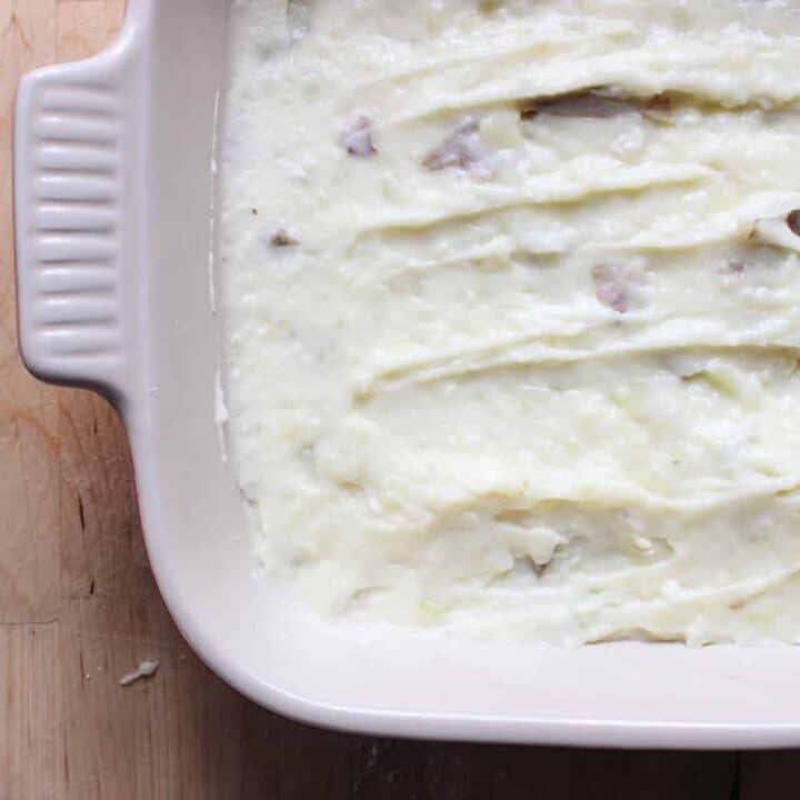 An overhead shot of mashed potatoes with brie in a cream baking dish.