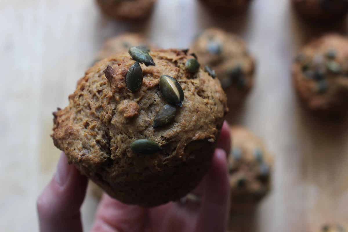 A close up shot of a sourdough pumpkin muffin with pumpkin seeds.