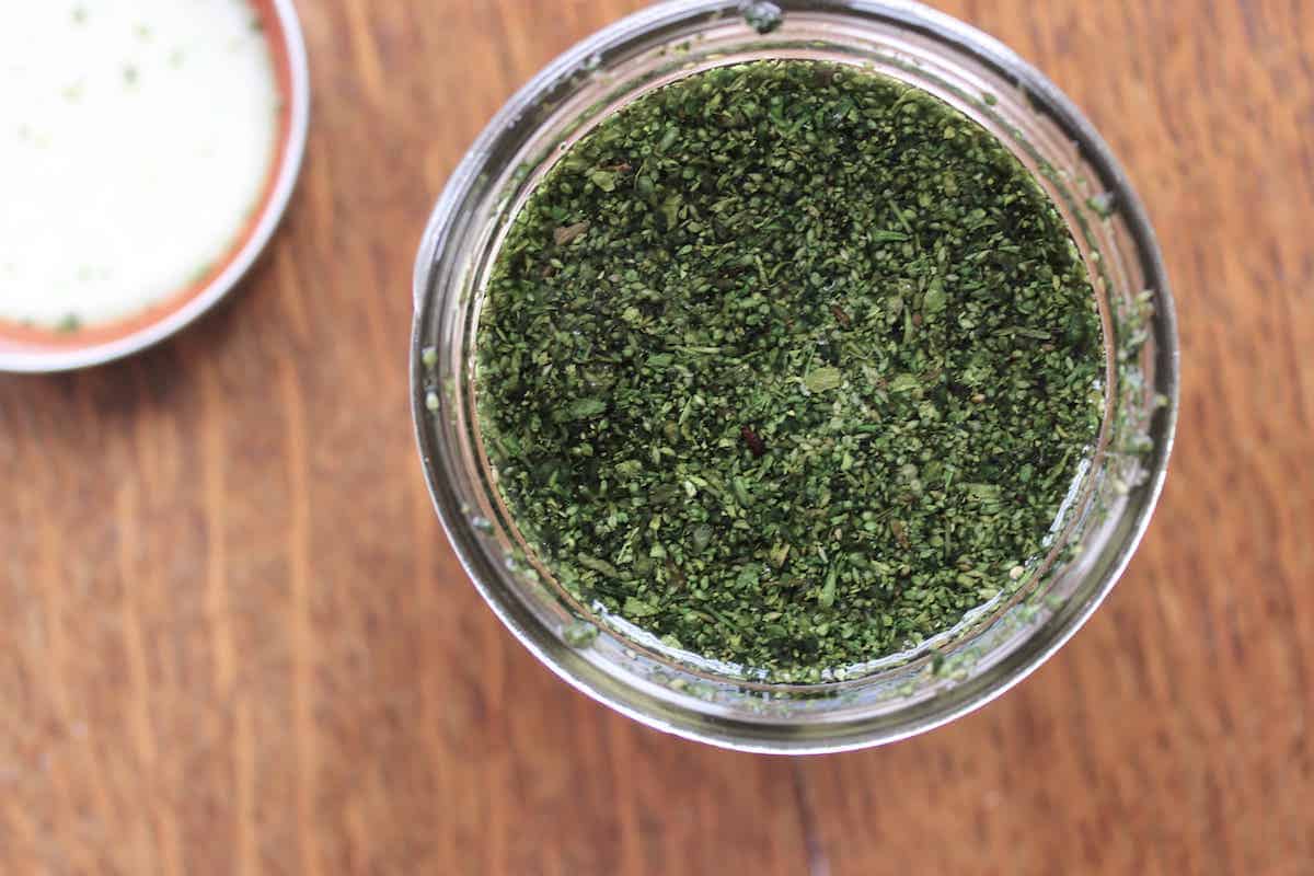 An overhead shot of stinging nettle in a glass jar with alcohol to make a tincture.