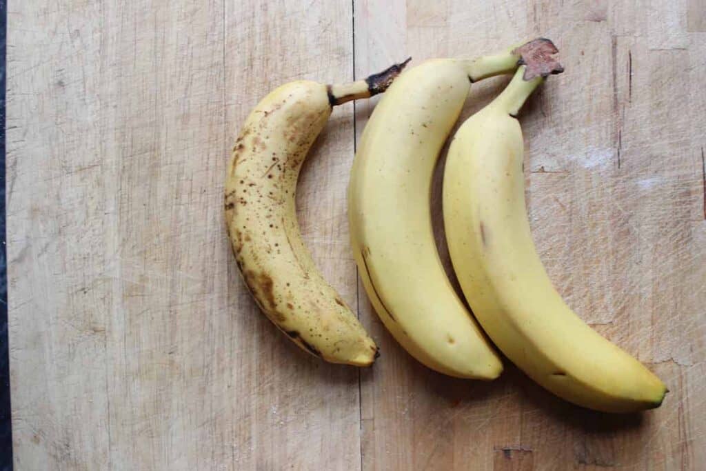 An overhead shot of three ripe bananas on a light countertop.