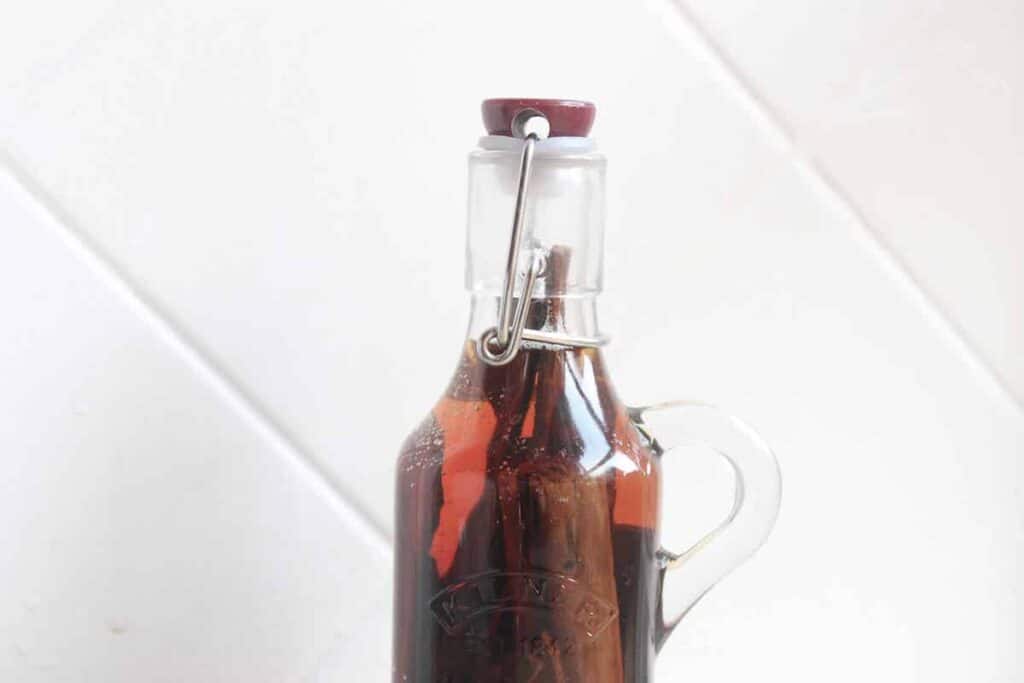 A close up of homemade cinnamon extract in a glass bottle.