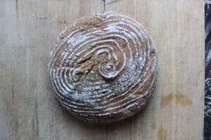 An overhead shot of a loaf of Parmesan Sourdough Bread with a spiral design on a light countertop.