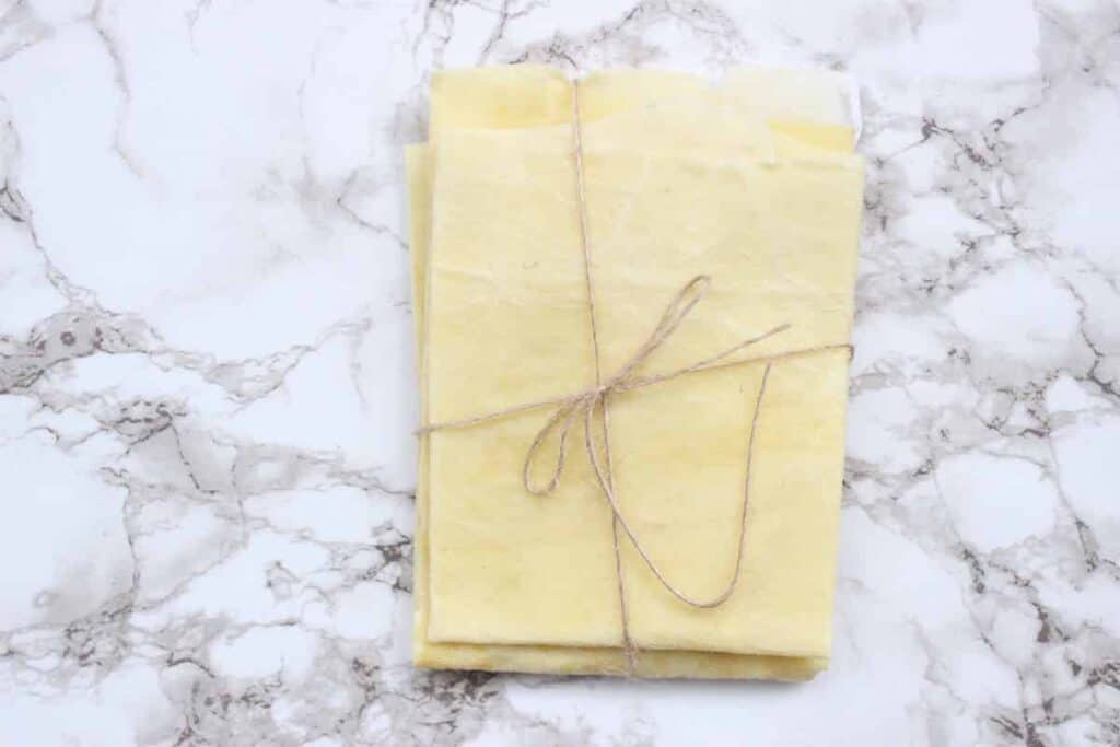An overhead shot of yellow homemade beeswax wraps tied in twine.