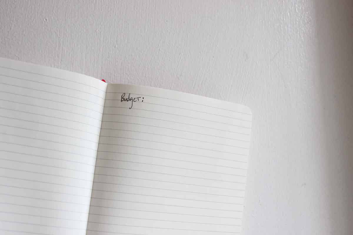 An open journal with the word budget written on the page against a white wall.