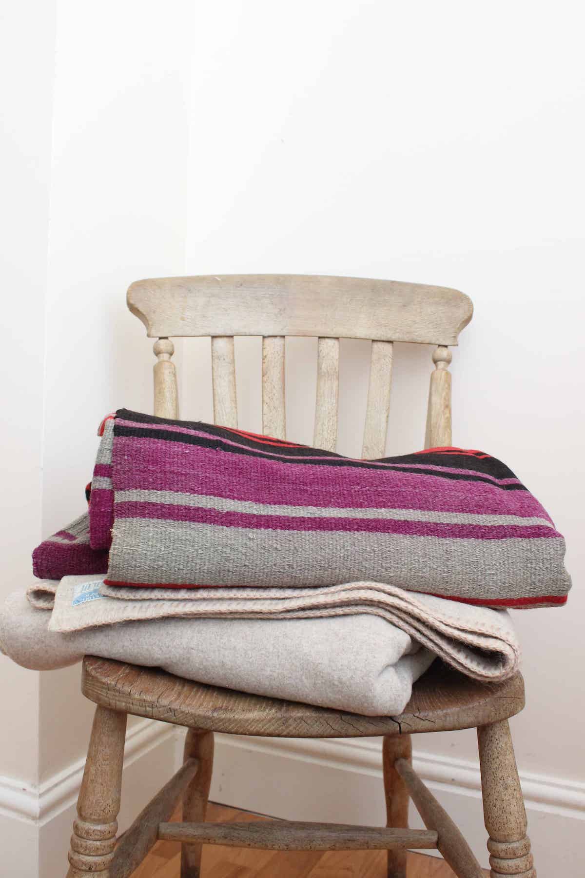 A shot of two wool blankets on a wooden chair.