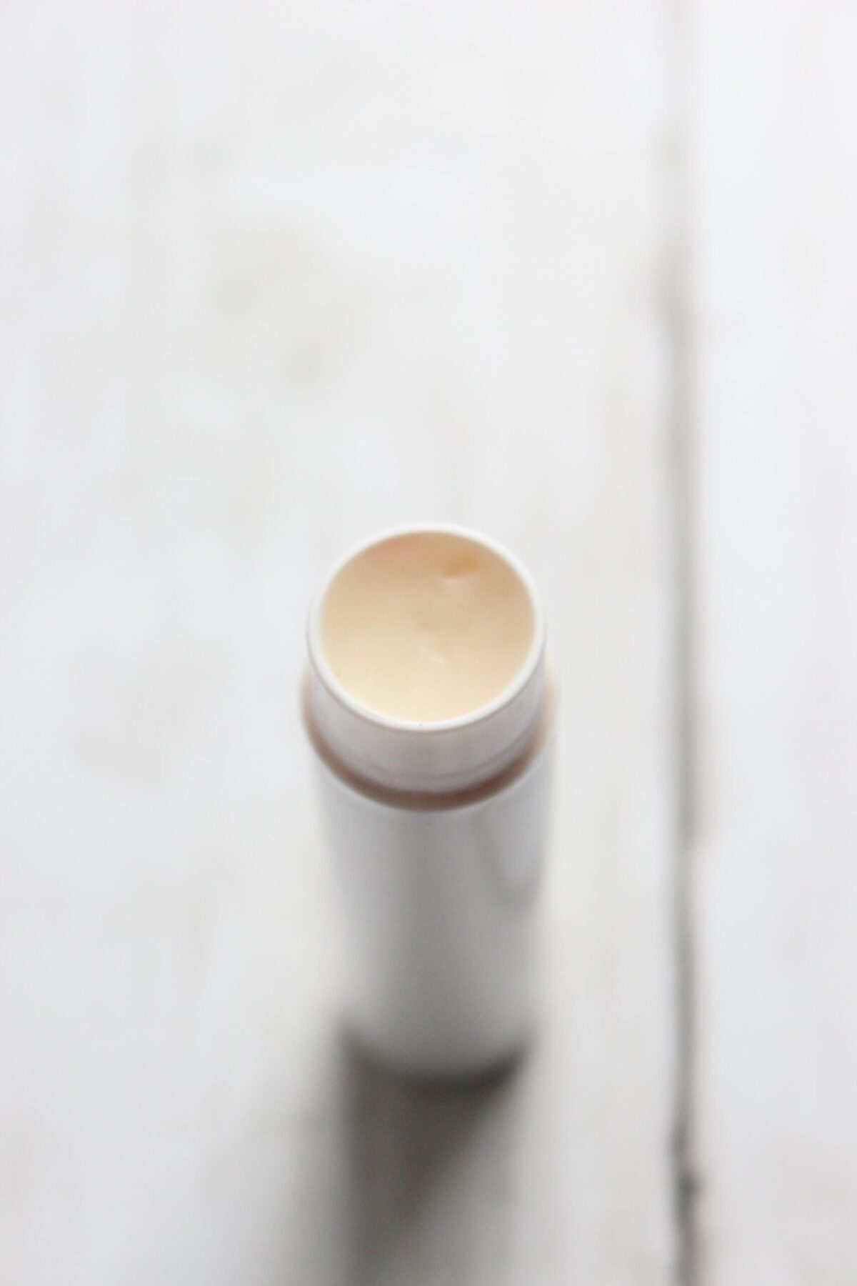 A close up of homemade shea butter lip balm in a white container.