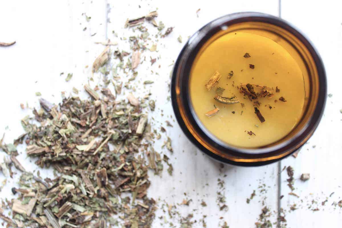 An overhead shot of DIY comfrey salve in a glass jar with dried comfrey next to it.