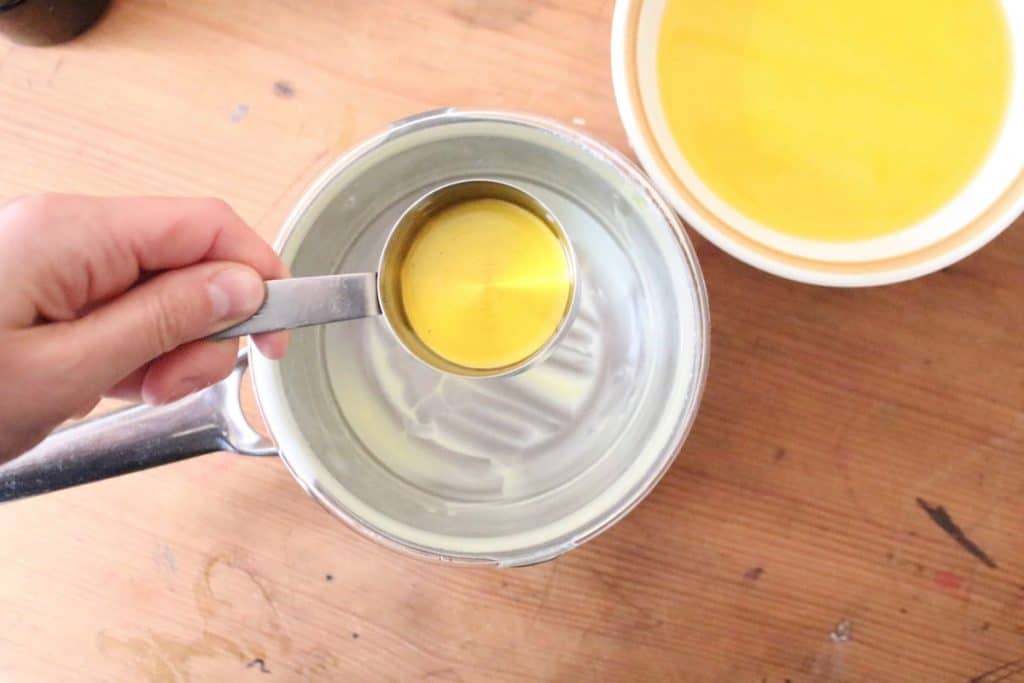 An overhead shot of calendula oil being added to a double boiler.