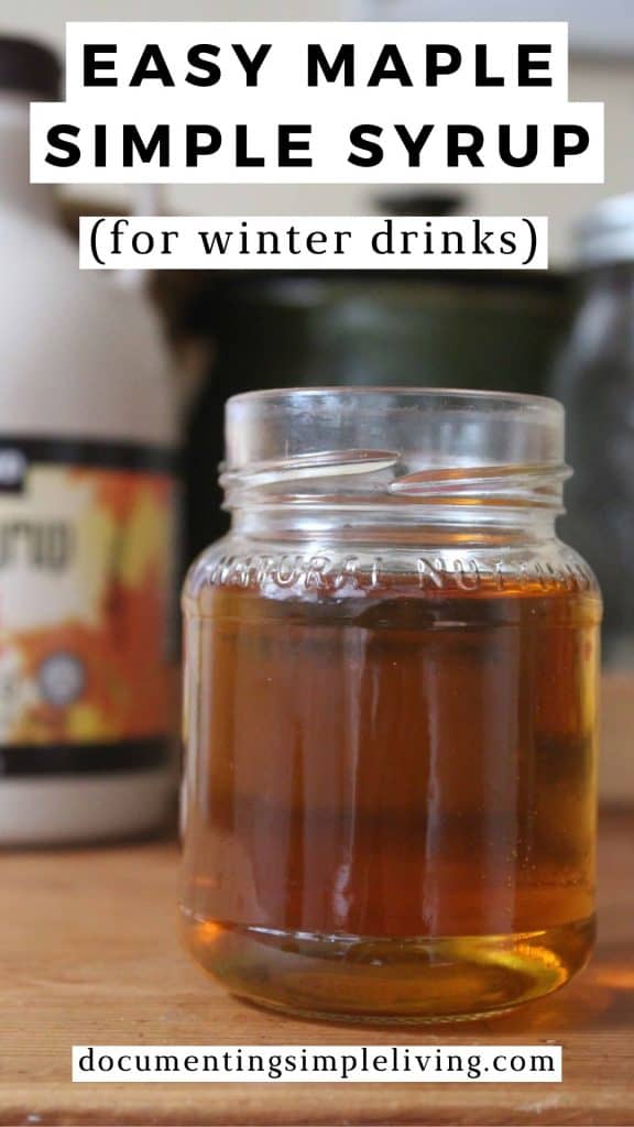 A small glass jar with maple simple syrup inside. There's a bottle of maple syrup in the background.